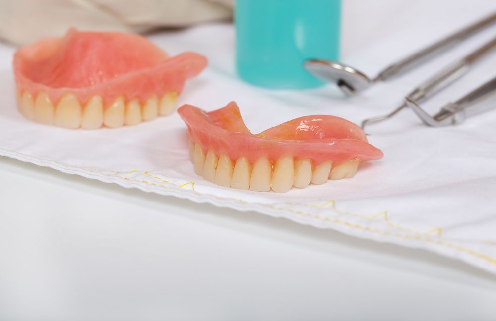 Dentures resting on a dental tray beside dental tools, prepared for fitting or adjustment.