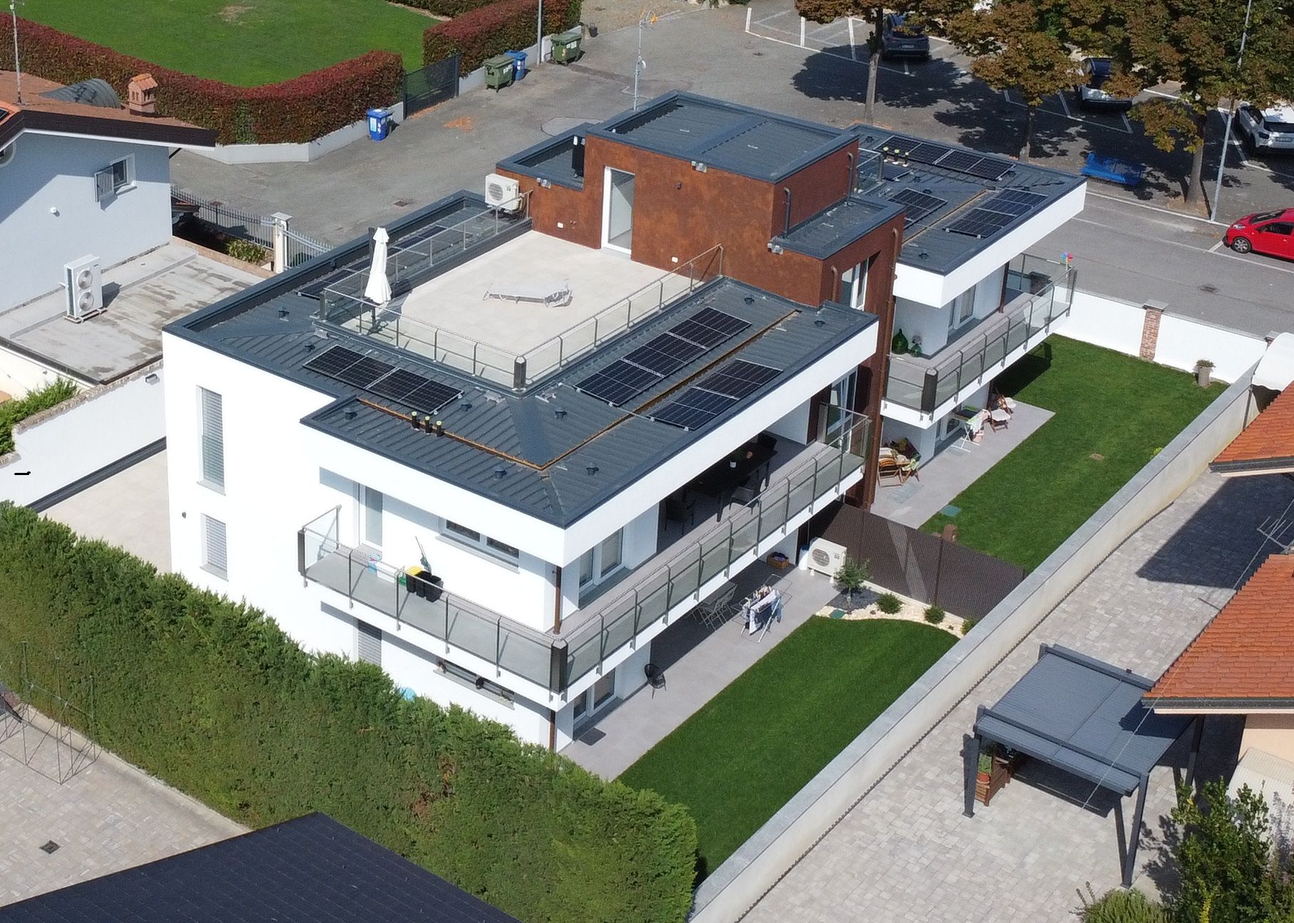 Dafne - Centallo. Vista aerea di una moderna casa bianca con un prato verde, circondata da altre case e da una strada.