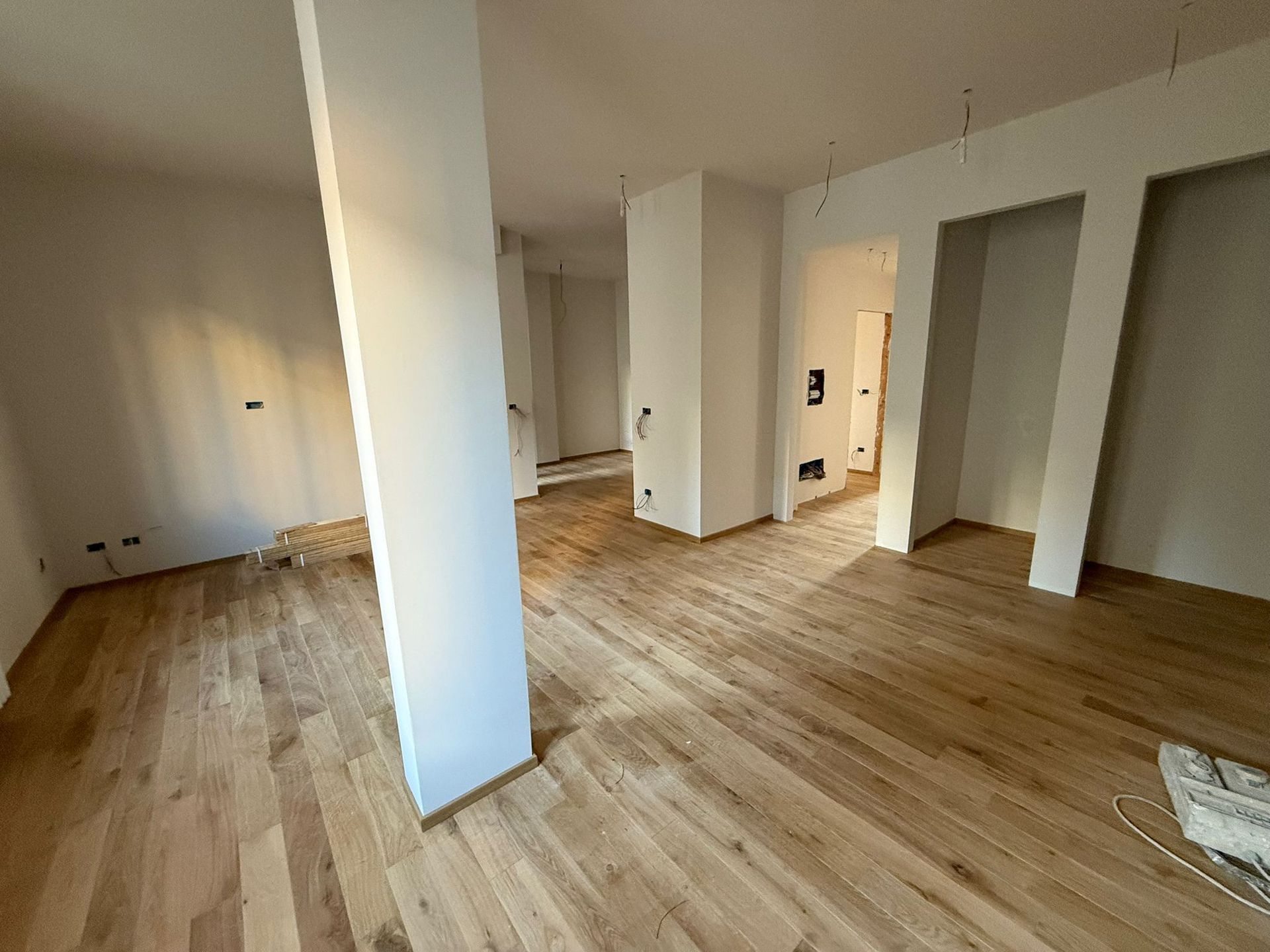 Cucina e sala da pranzo moderne con ripiani in marmo, mobili in legno chiaro e sedie beige.