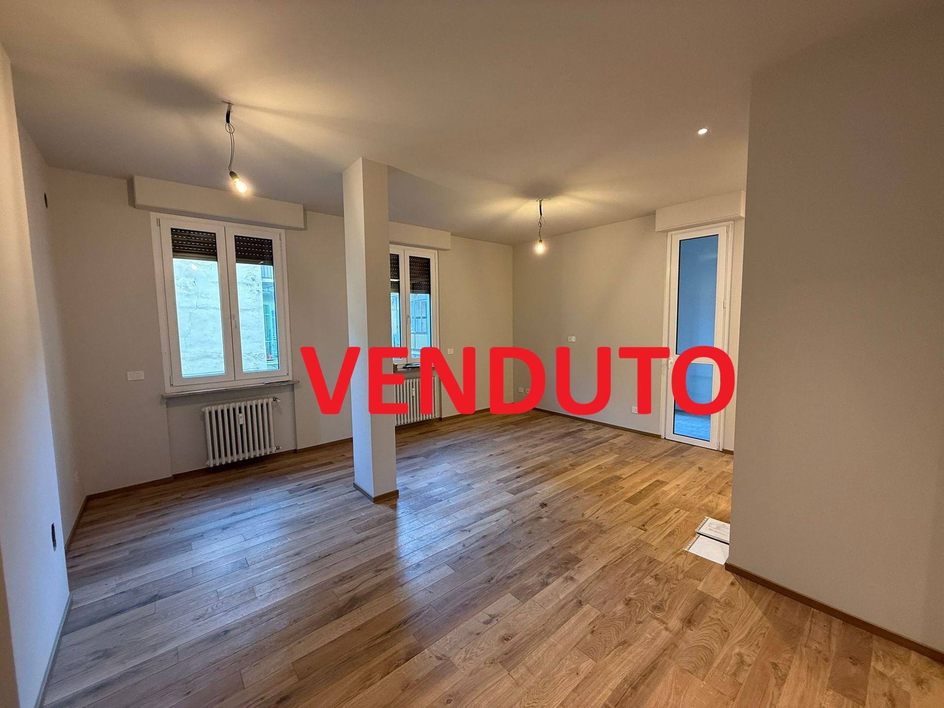 Cucina e sala da pranzo moderne con ripiani in marmo, mobili in legno chiaro e sedie beige.