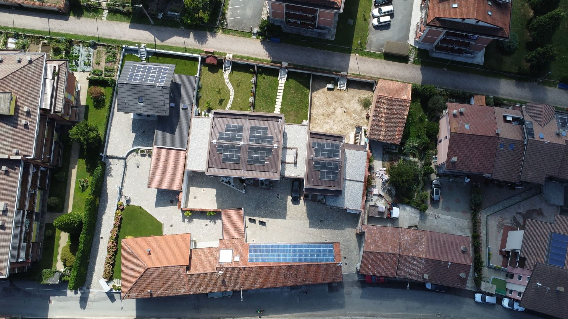 Callimaco - Centallo. Vista aerea di edifici con tetti di tegole rosse, pannelli solari e giardini verdi