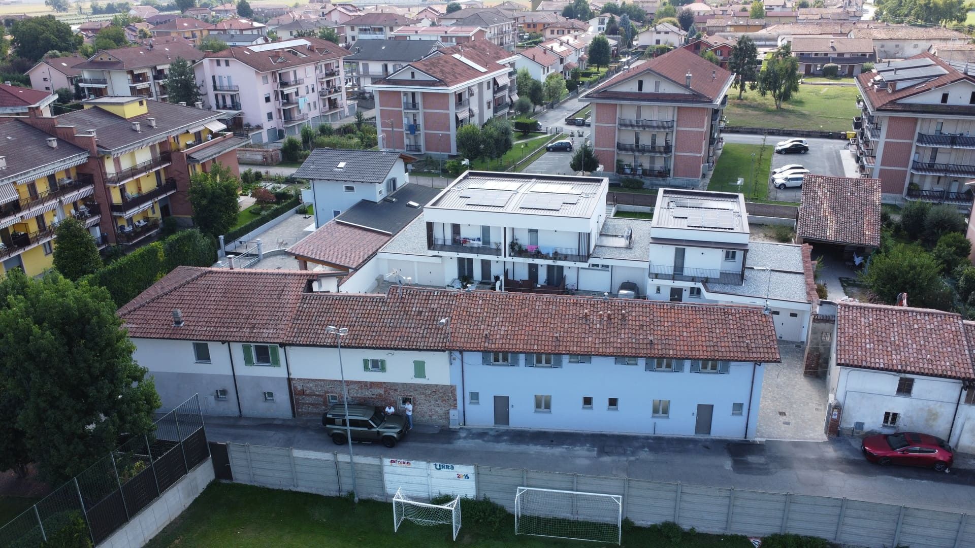 Callimaco - Centallo. Vista aerea di edifici residenziali, per lo più in mattoni, con tetti rossi e bianchi, in una città.