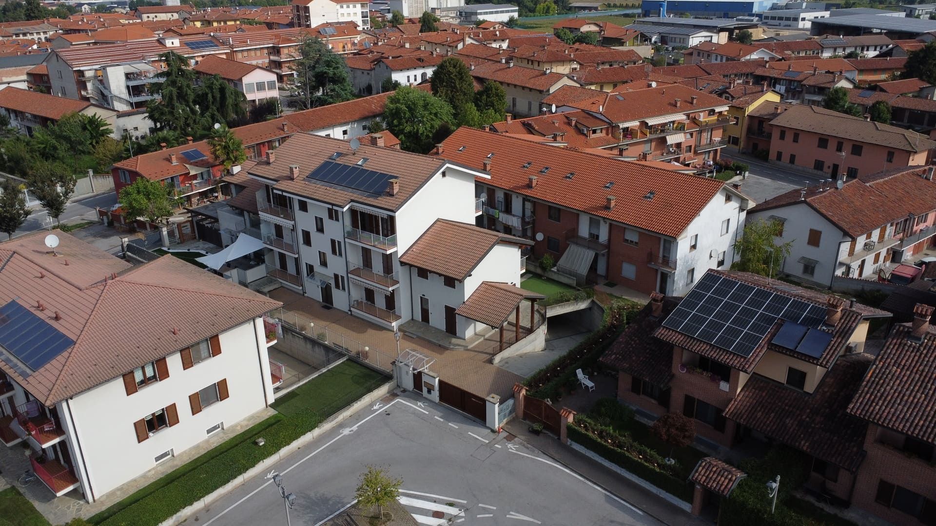 Isotta - Villafalletto. Vista aerea di una zona residenziale con tetti di tegole rosse, edifici bianchi e marroni.