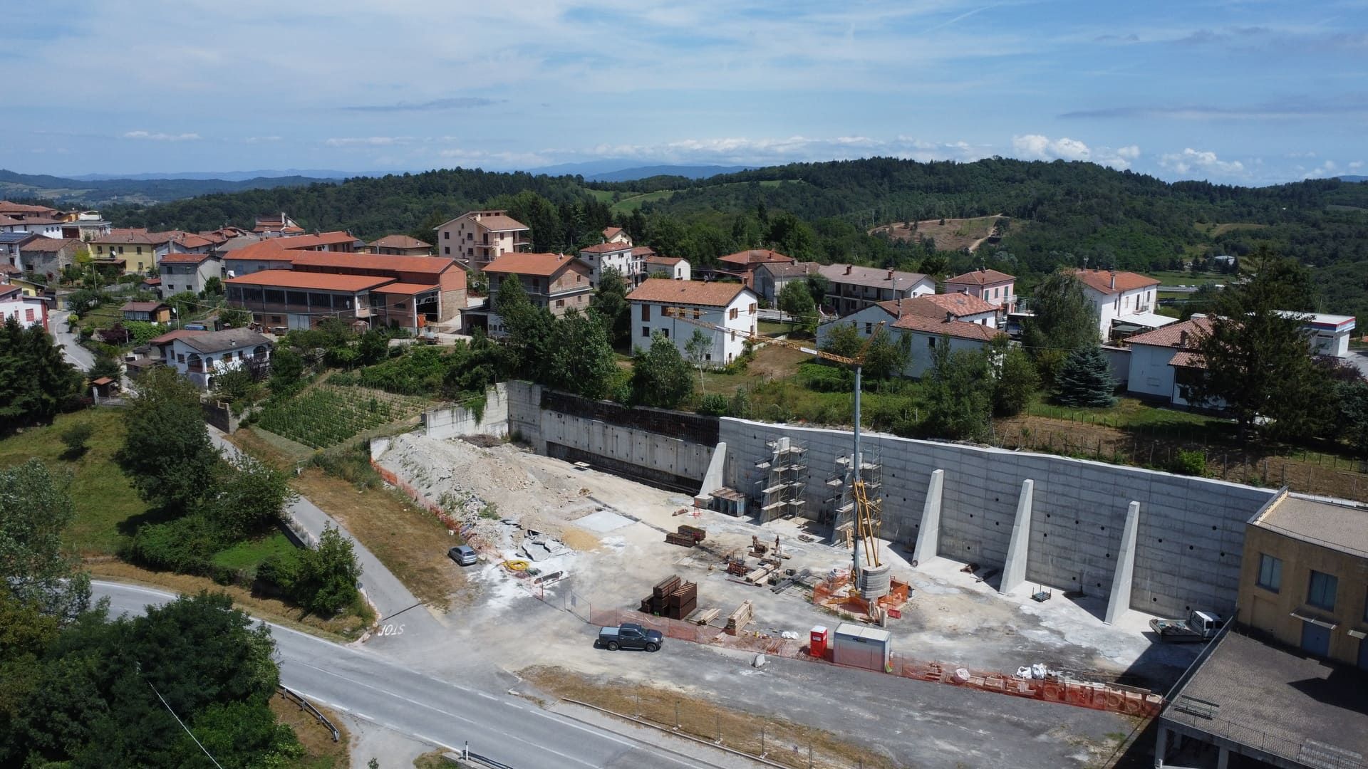 Cantiere con muro di contenimento, città sullo sfondo, giornata di sole.