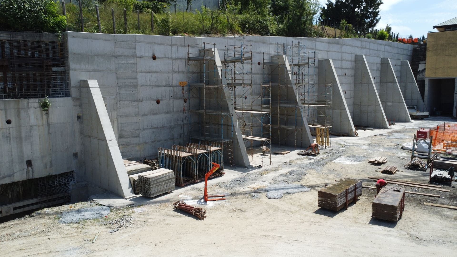 Muro di contenimento in cemento in costruzione con contrafforti angolari.