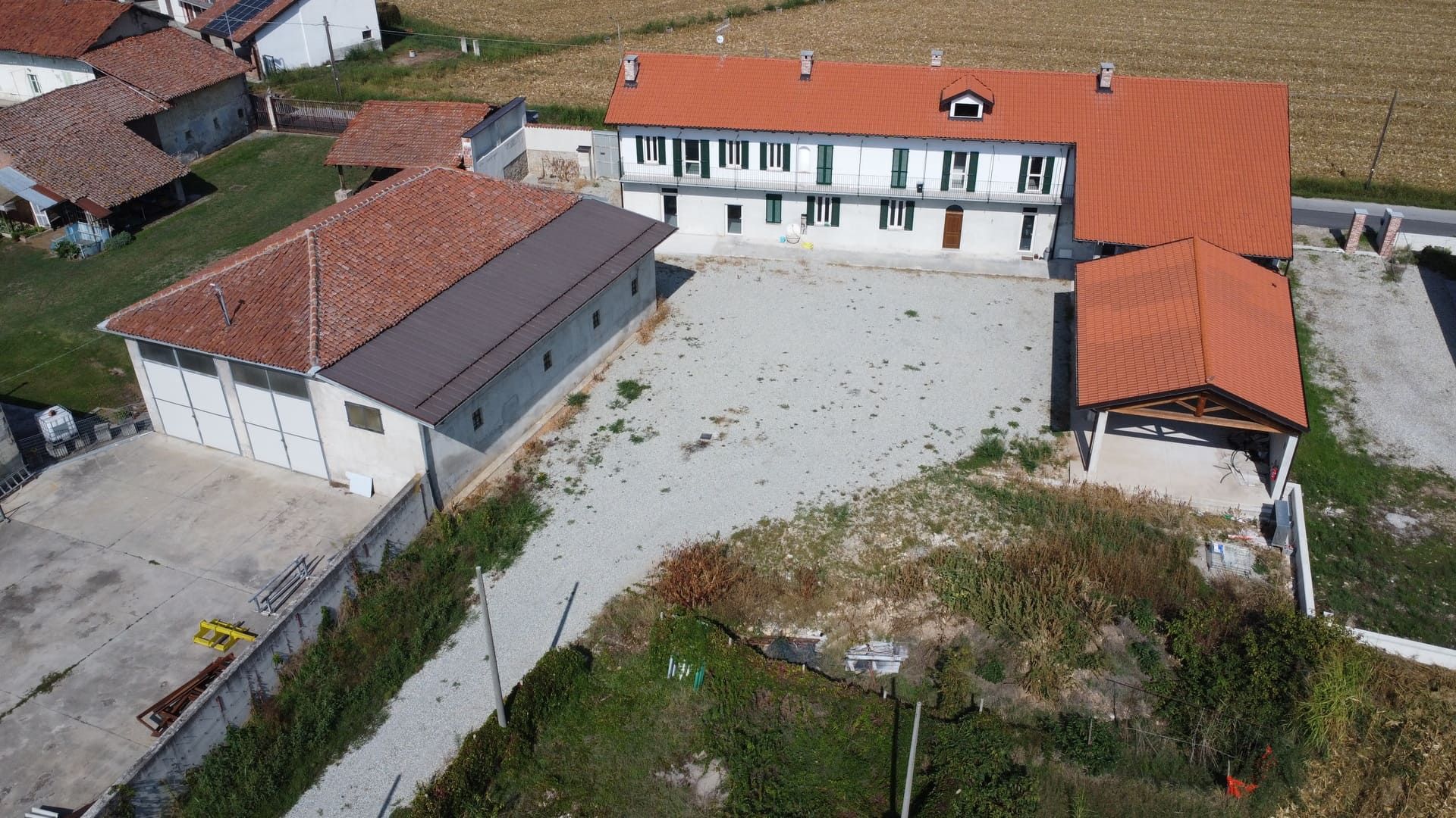 Vista aerea di una proprietà rurale con diversi edifici, tra cui una casa a due piani con tetto in tegole rosse.