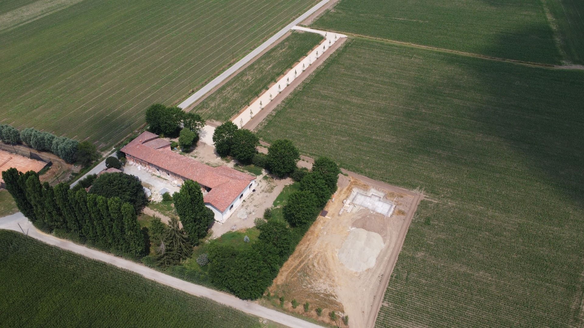 Vista aerea di un edificio circondato da alberi e campi, probabilmente un vigneto.
