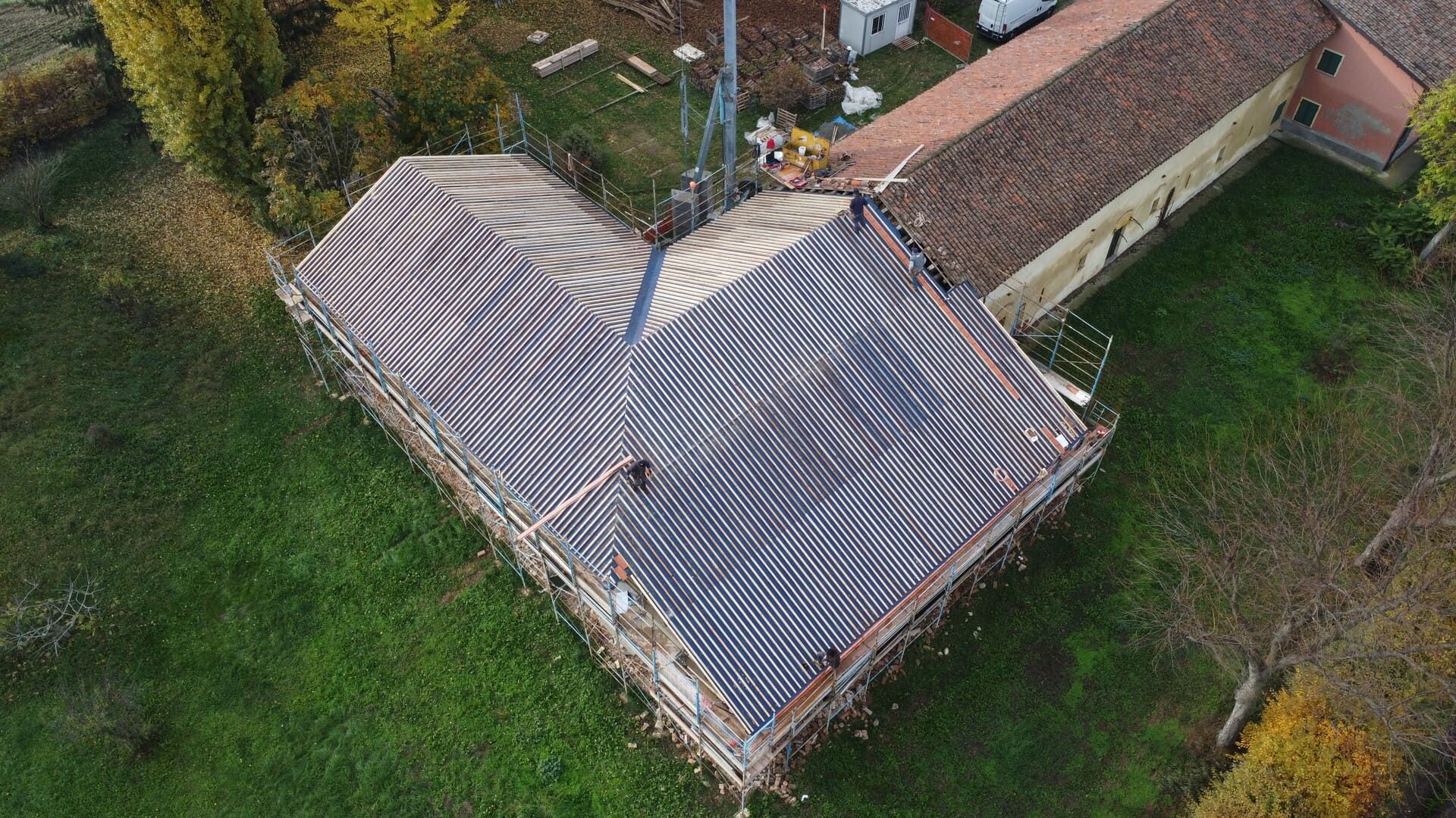 Vista aerea del tetto di un edificio a forma di cuore, con tetto in tegole marroni, su un'area erbosa.