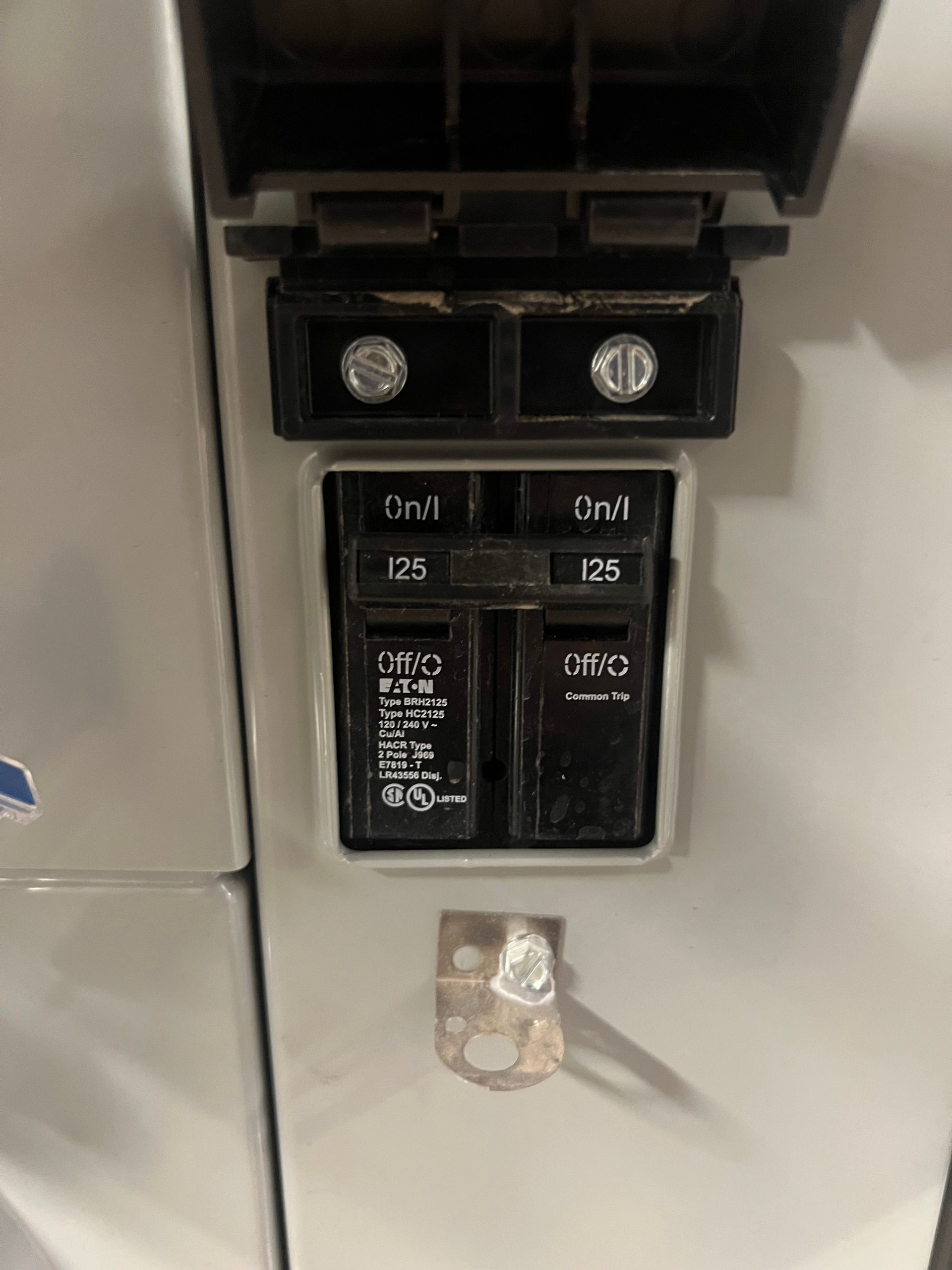 Circuit breaker panel with two switches, labels, and screw terminals, partially open.