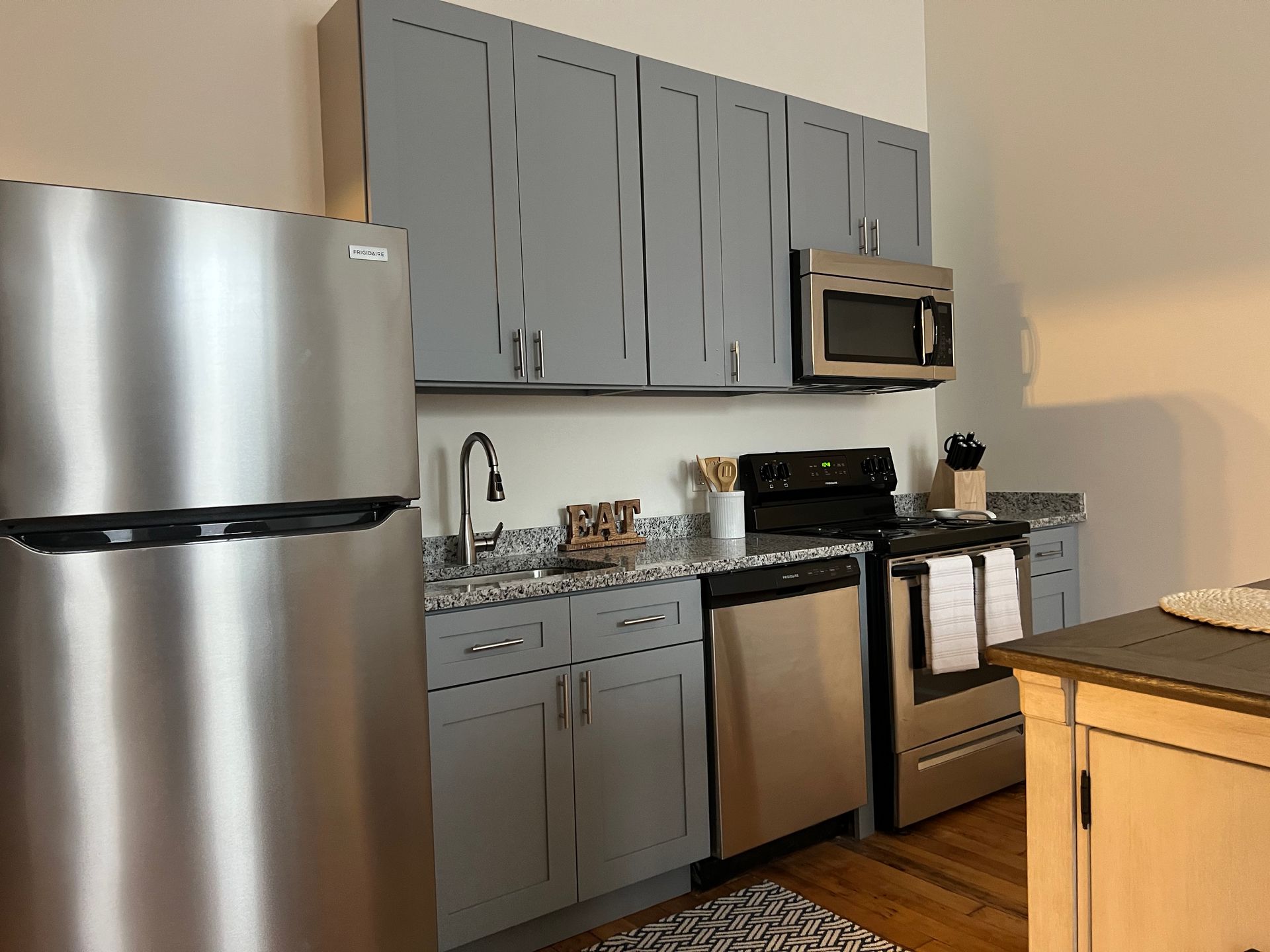 Modern kitchen with gray cabinets, stainless steel appliances, and granite countertops.