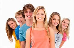 Grupo de jóvenes sonrientes, vistiendo camisetas coloridas, posando juntos frente a un fondo blanco.