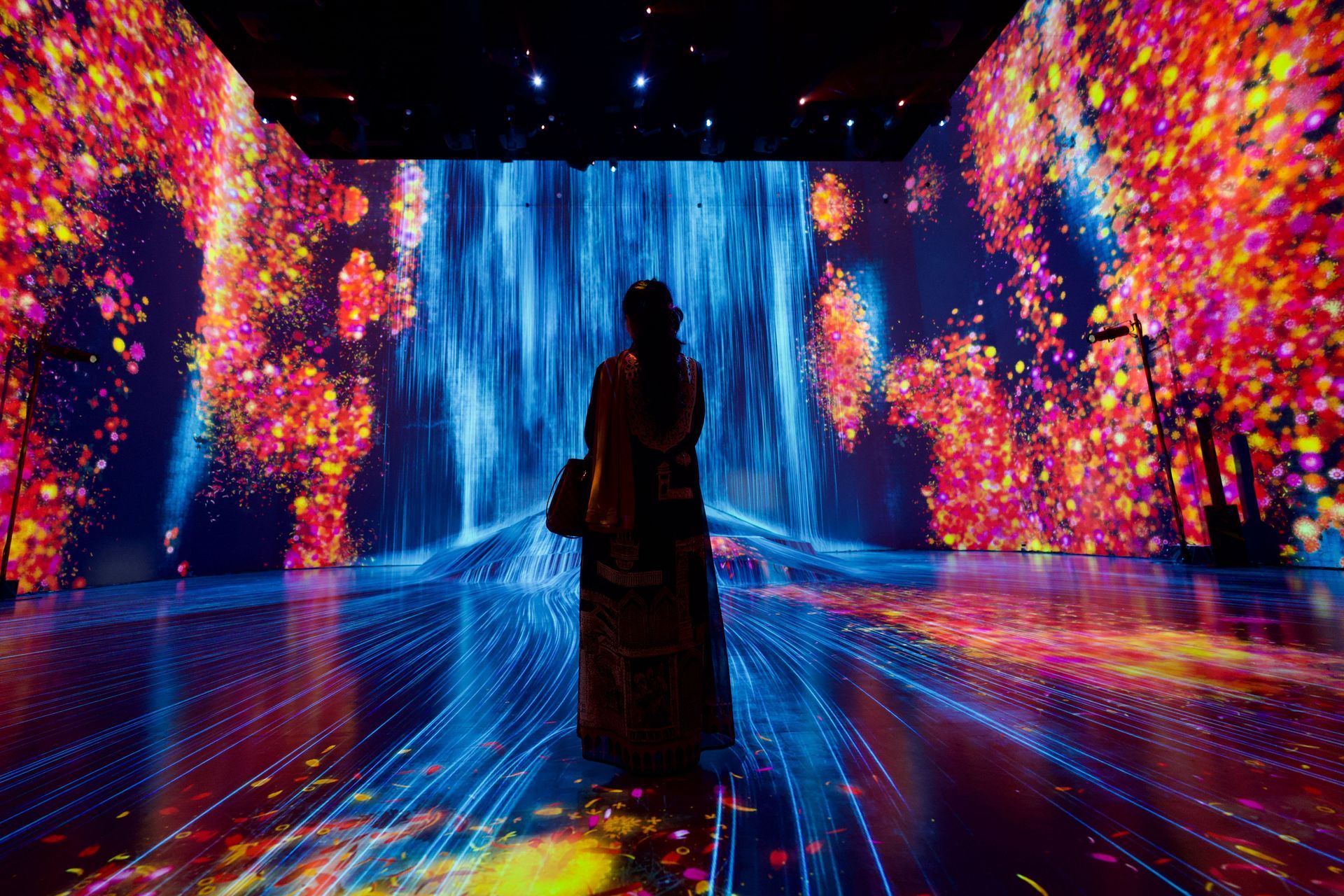A woman is standing in front of a large screen with a waterfall projected on it.