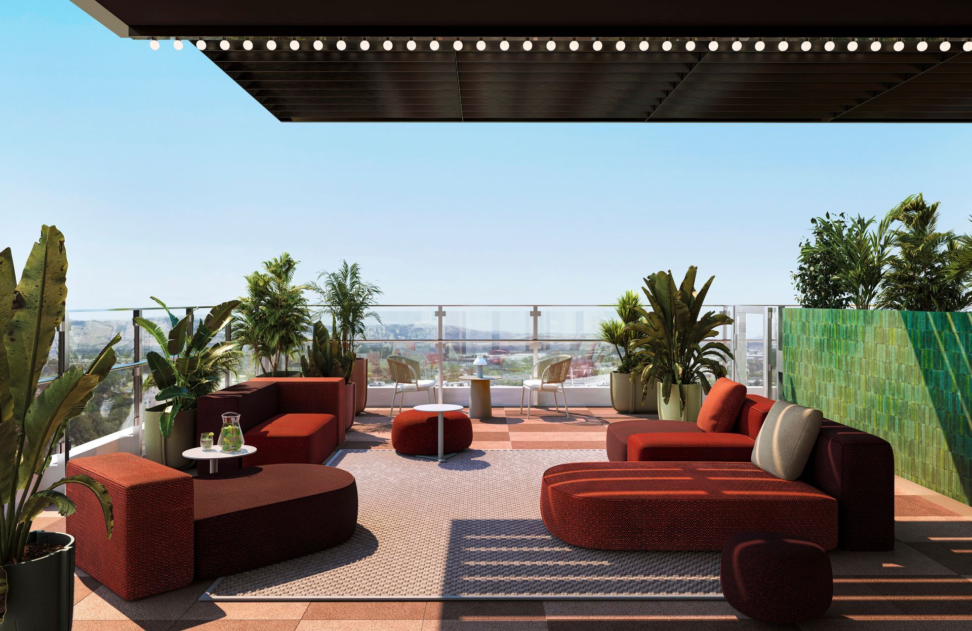 Rooftop lounge with red-orange seating, potted plants, and city view under a blue sky.