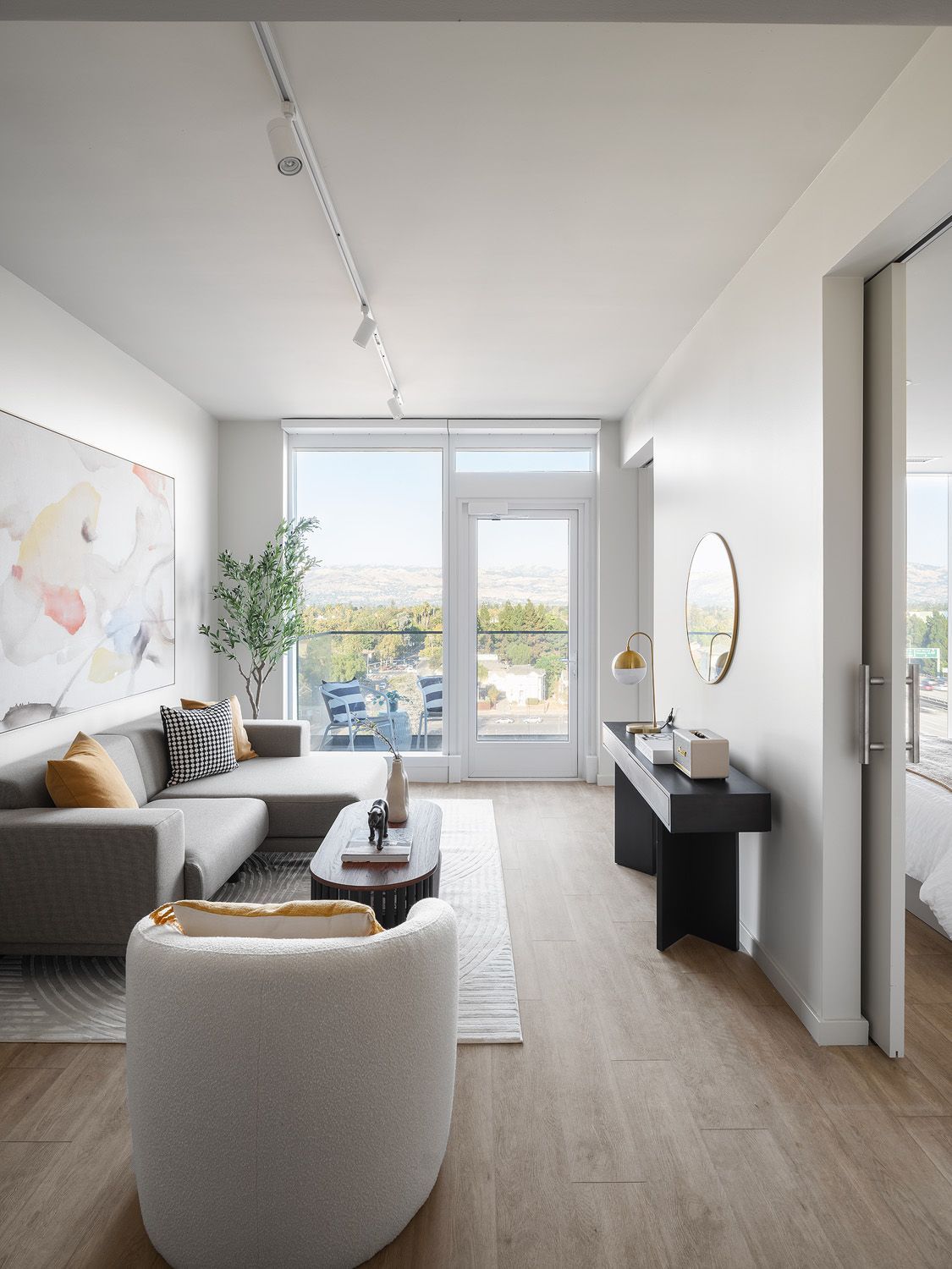 Modern living room with a sectional sofa, coffee table, and large window overlooking a city.