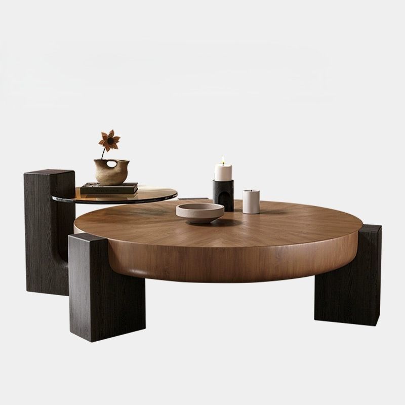Round wooden coffee table with dark legs and a side shelf; decor.