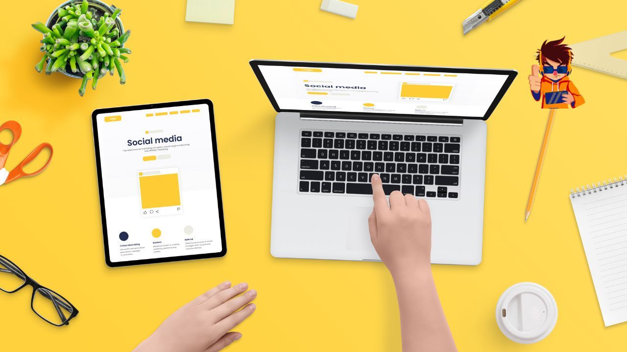 A person is using a laptop and a tablet on a yellow table.