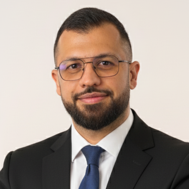 Man in suit with glasses and beard, smiling at the camera.