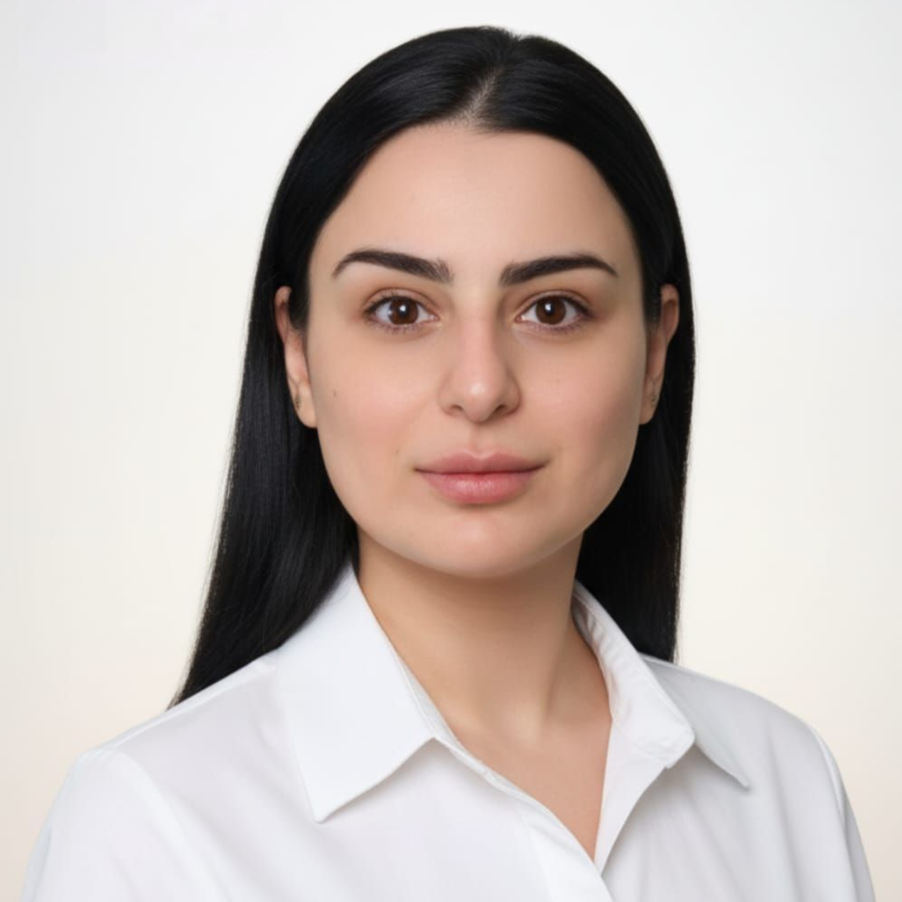 Woman with dark hair and brown eyes wearing a white shirt, looking directly at the camera.