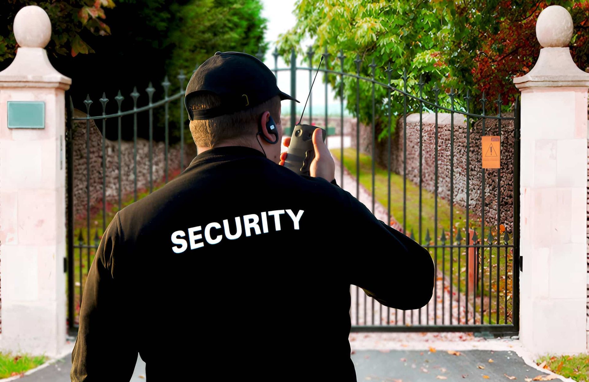 A Security Guard is Standing in Front of a Gate Talking on a Walkie Talkie — CTE Systems In Hallidays Point, NSW
