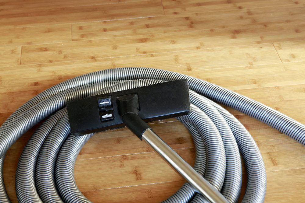 A Vacuum Cleaner Hose is Laying on a Wooden Floor — CTE Systems In Forster, NSW