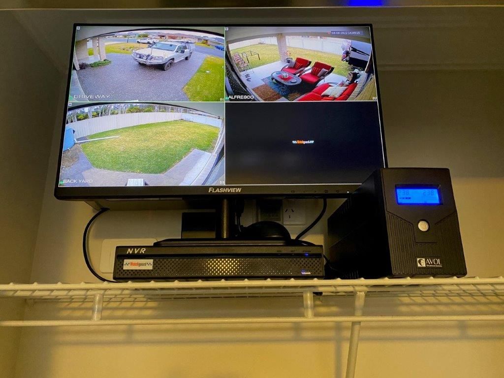 A Man is Holding a Tablet With a Security Camera on It — CTE Systems In Hallidays Point, NSW