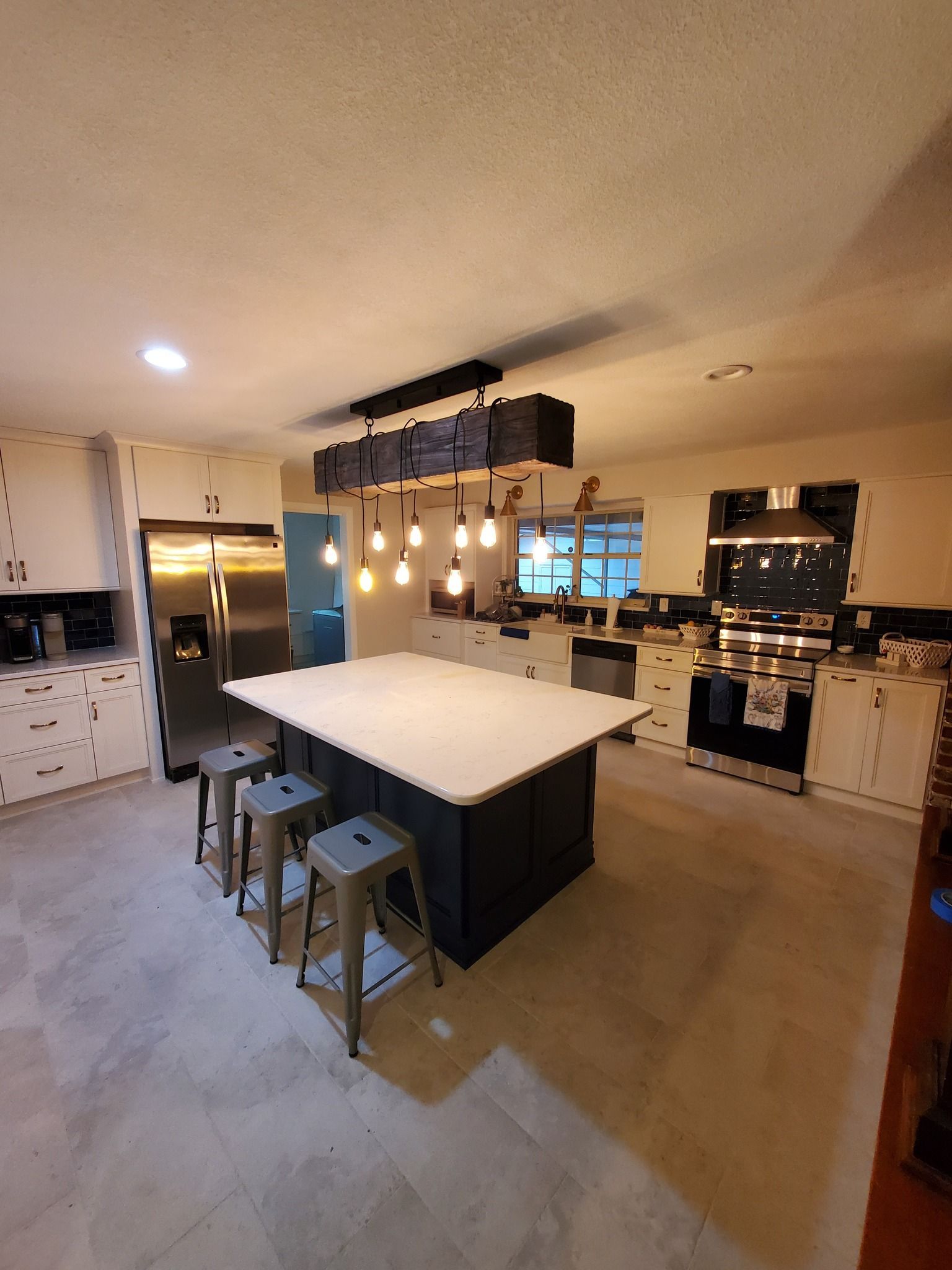 Modern kitchen with white cabinets, large island, and stainless steel appliances.