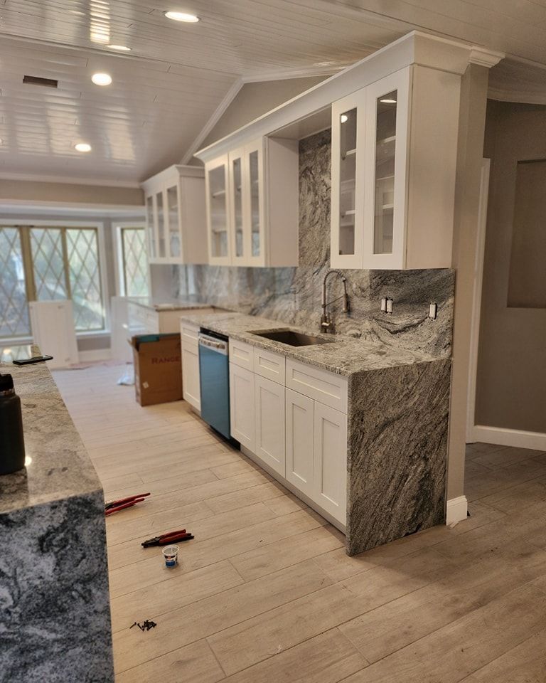 Newly renovated kitchen with white cabinets, gray granite countertops, and light wood-look flooring.