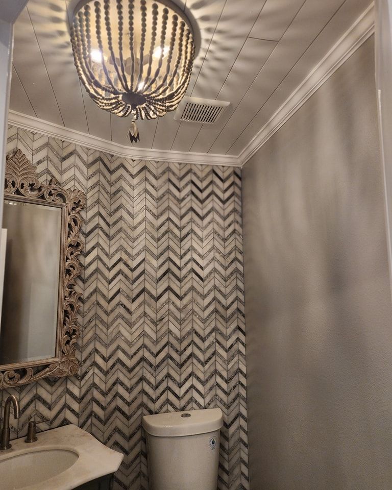 Bathroom with decorative tile, a toilet, and a chandelier.