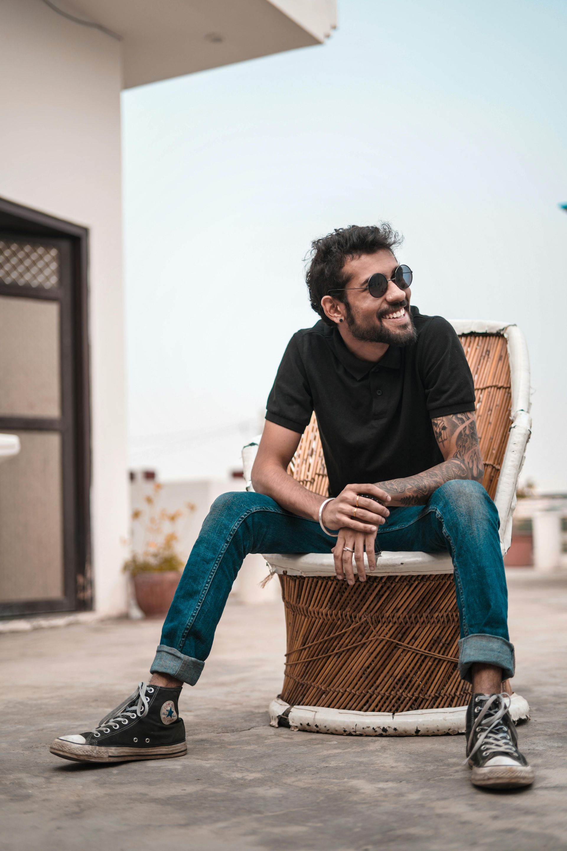 A man is sitting on a chair wearing sunglasses and a black shirt.