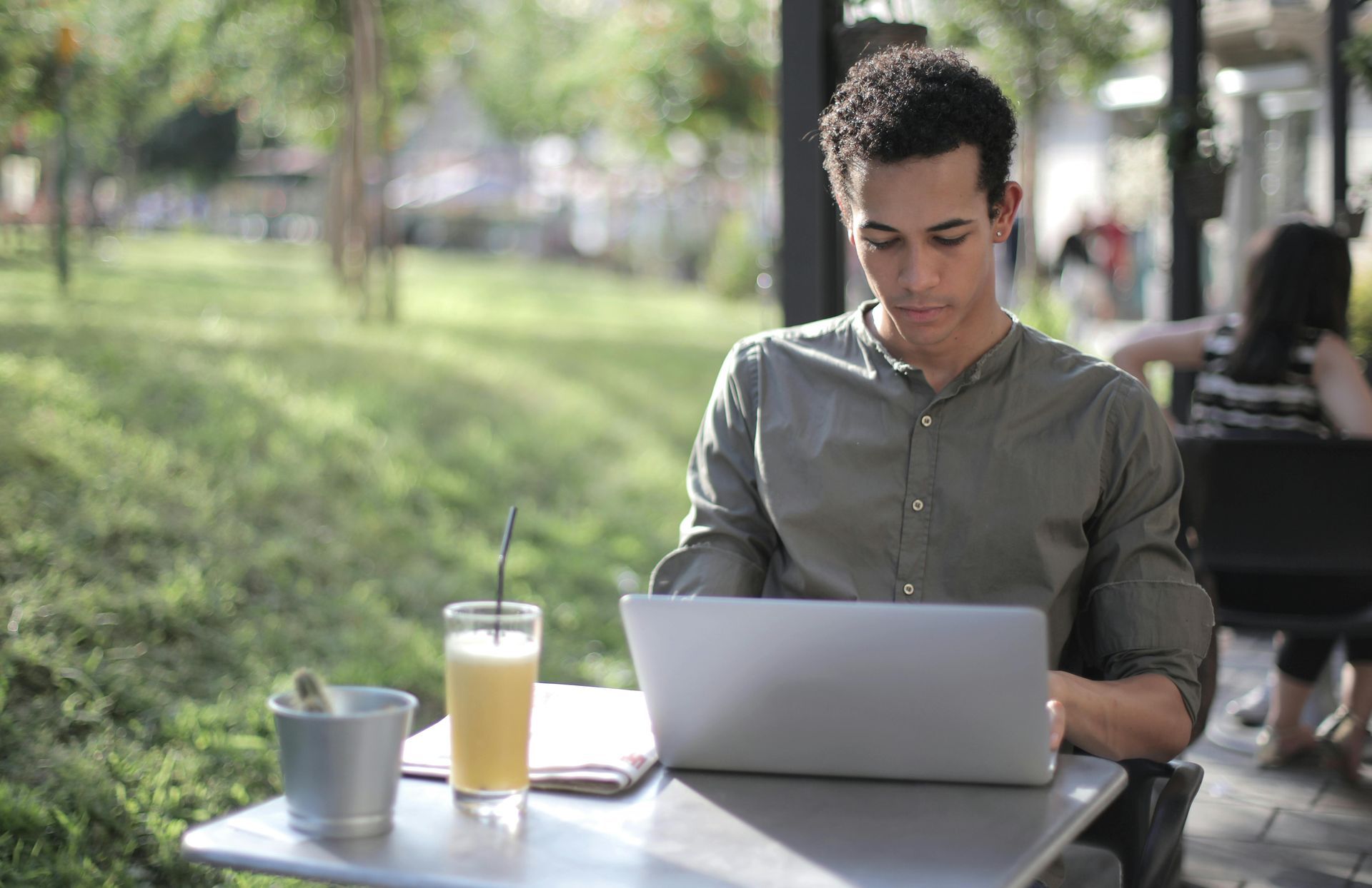 A man is sitting at a table using a laptop computer.