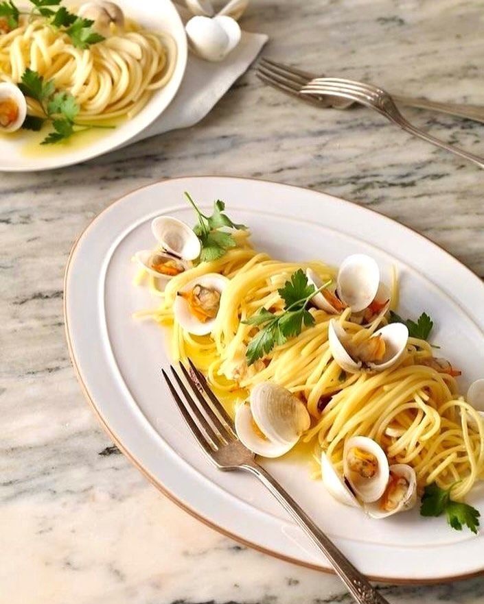 Un piatto bianco condito con spaghetti e vongole con una forchetta