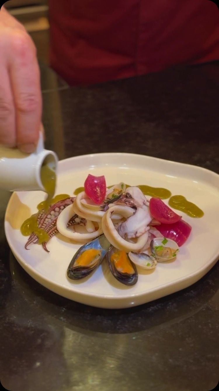 Una persona sta versando la salsa su un piatto di cibo.