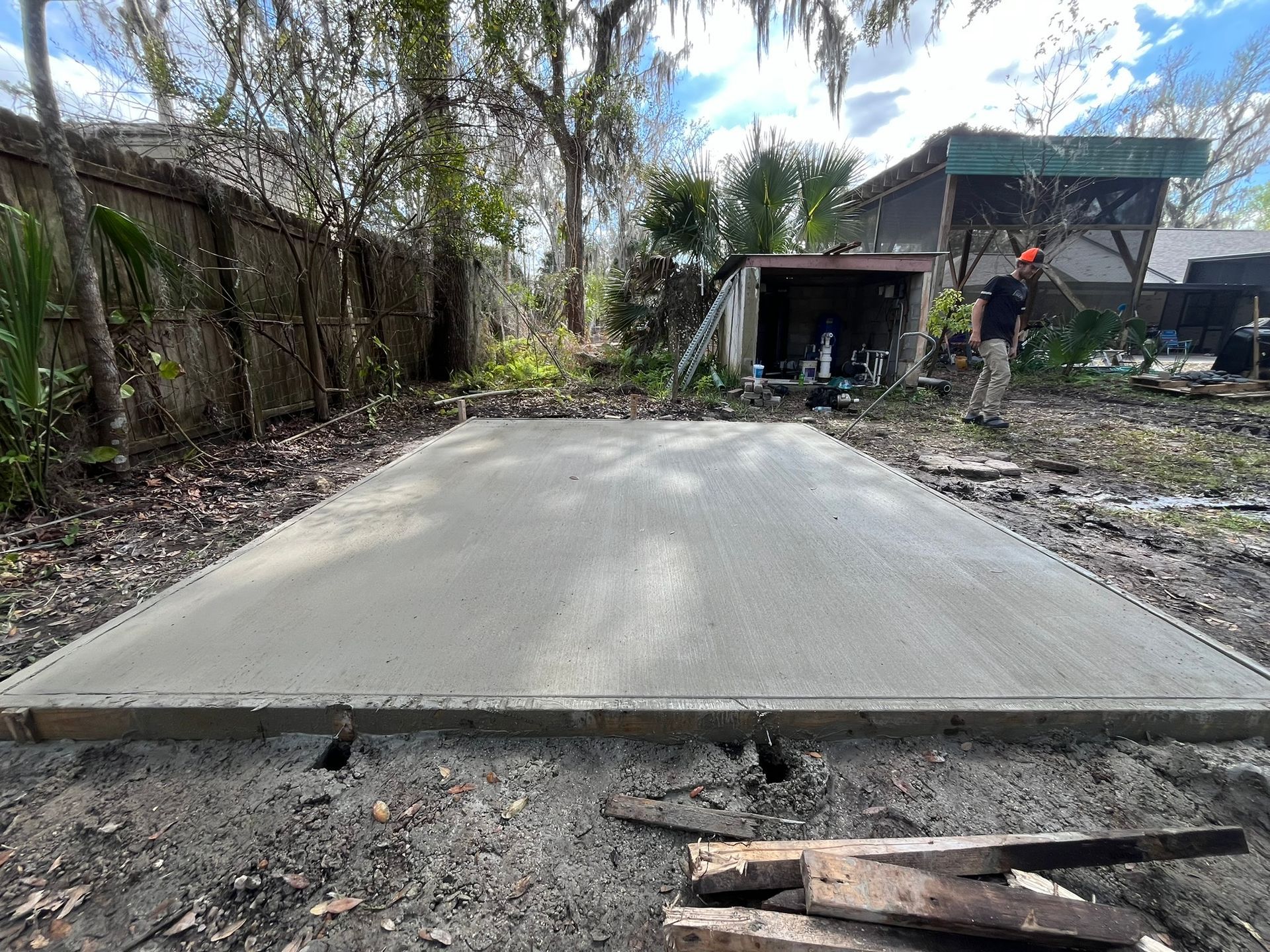 Samuel Site Service freshly poured a smooth concrete slab in DeBary, FL, with trees, a shed, and too