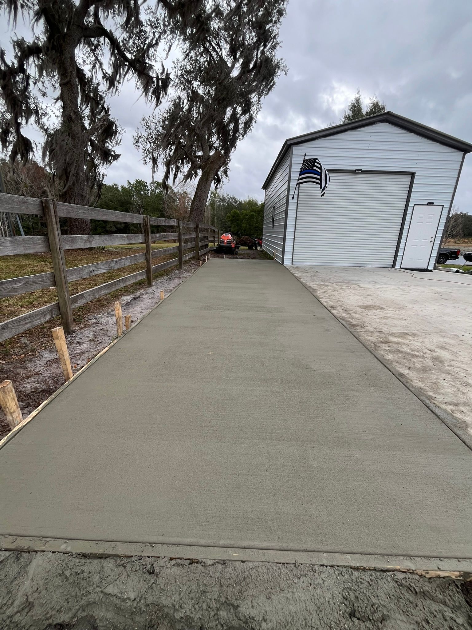 A concrete driveway leading to a garage with a wooden fence.