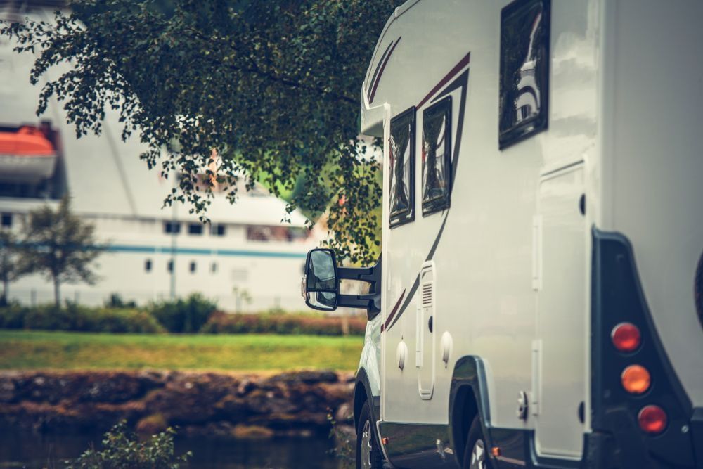 A White RV is Parked Under a Tree Next to a River — Airlie Beach Exhaust and Mechanical In Whitsundays, QLD
