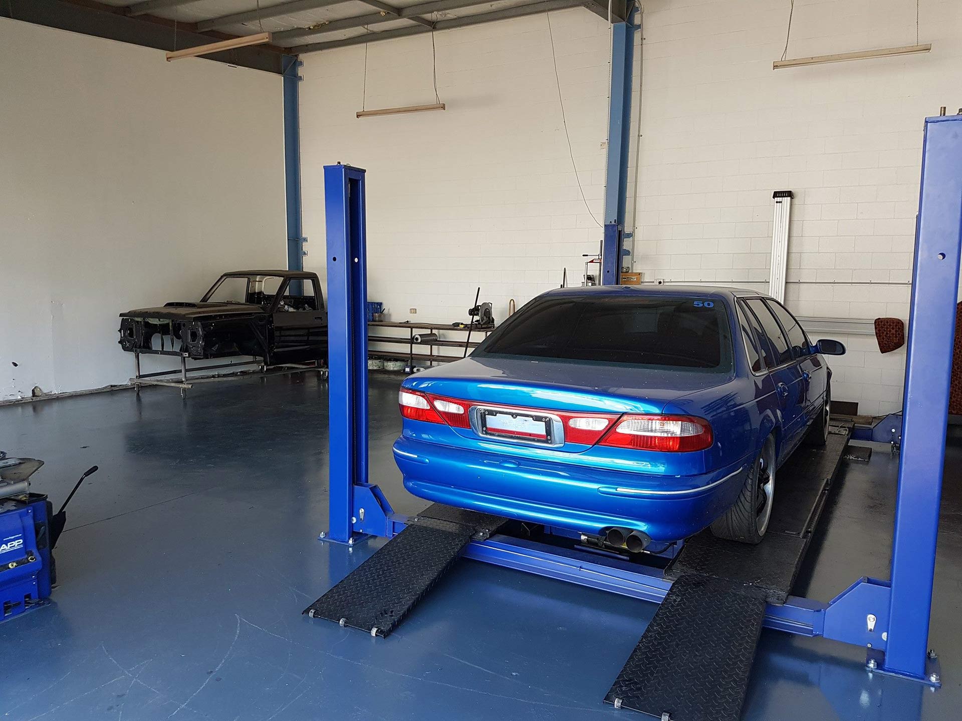 A Blue Car Is On A Lift In A Garage — Airlie Beach Exhaust and Mechanical In Cannonvale, QLD