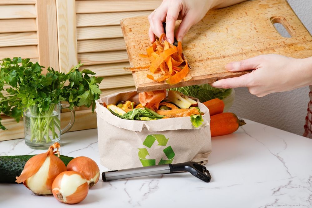 A person is cutting carrots on a cutting board and putting them in a bag.