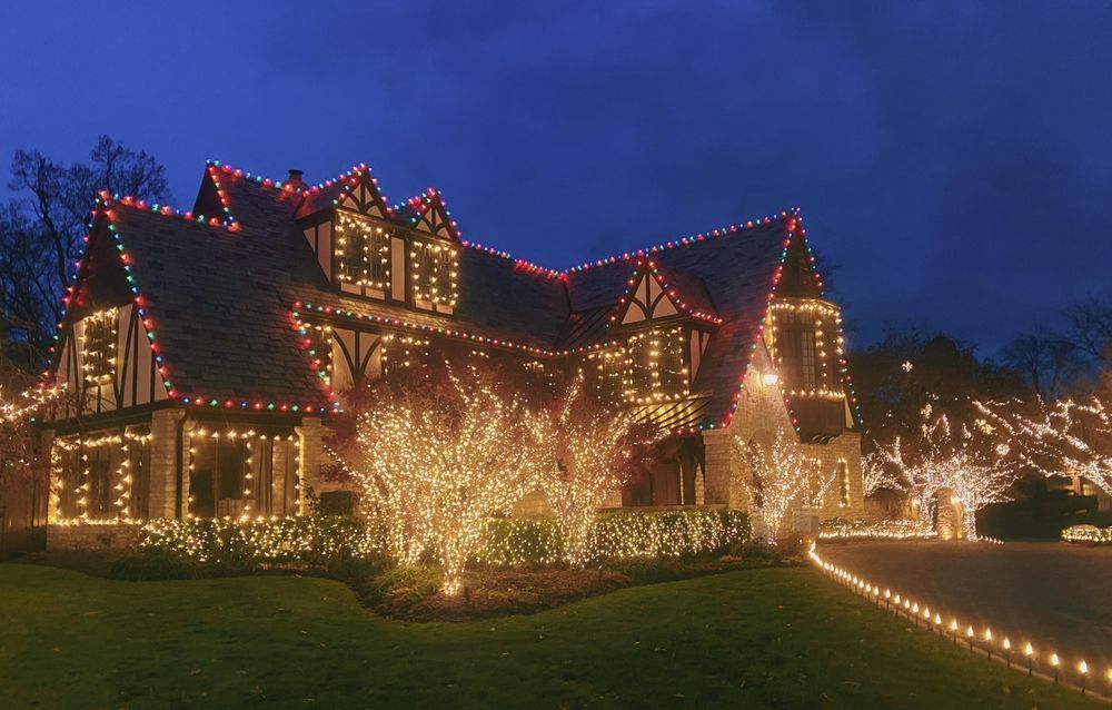 A large house is decorated with christmas lights at night.