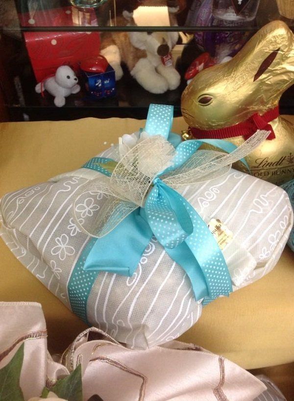un pacco regalo con un nastro azzurro e accanto un cioccolato a forma di coniglio