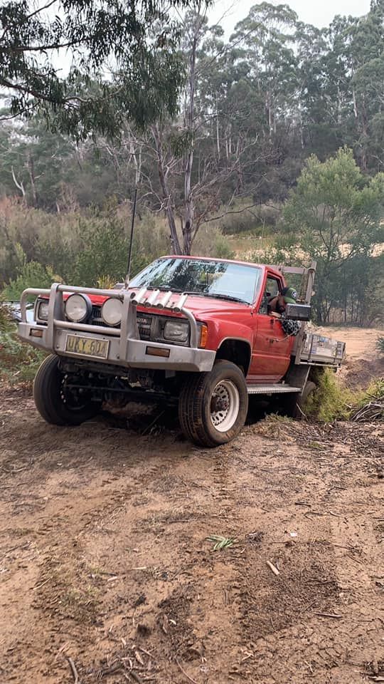 Red Pickup Truck Driving on A Dirt Road in A Wooded Area — D.A.G Automotive in Unanderra, NSW
