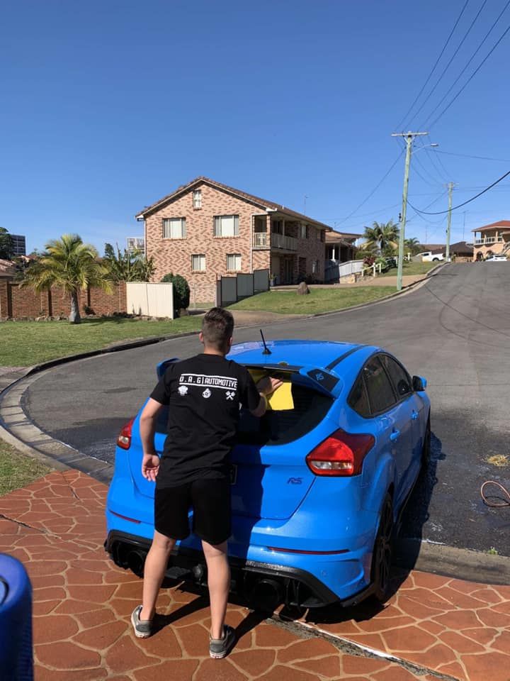 Person Washing a Bright Blue Car in Front of a House — D.A.G Automotive in Unanderra, NSW