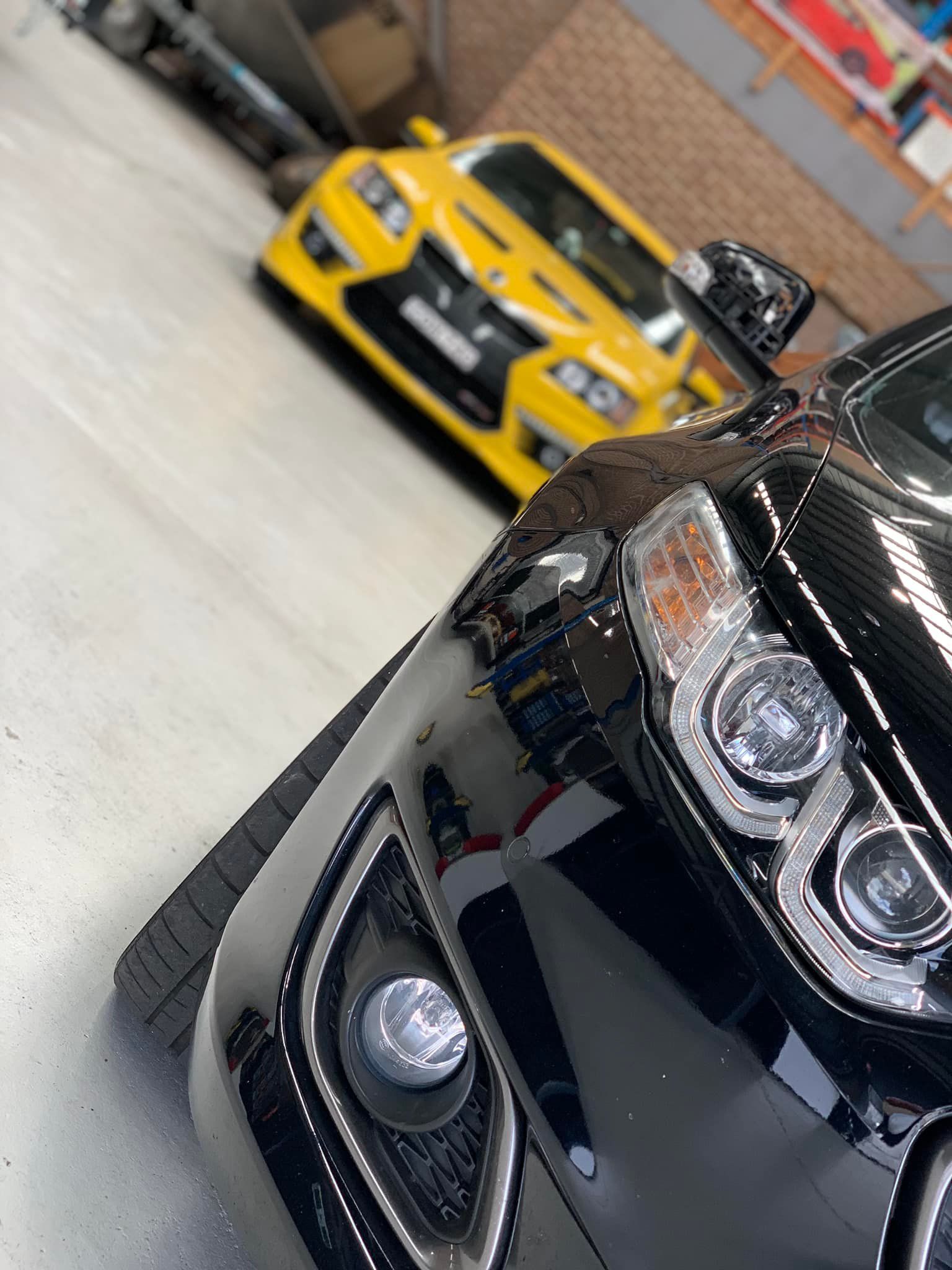 Black Car in Focus, Yellow Car Blurred in Background — D.A.G Automotive in Wollongong, NSW