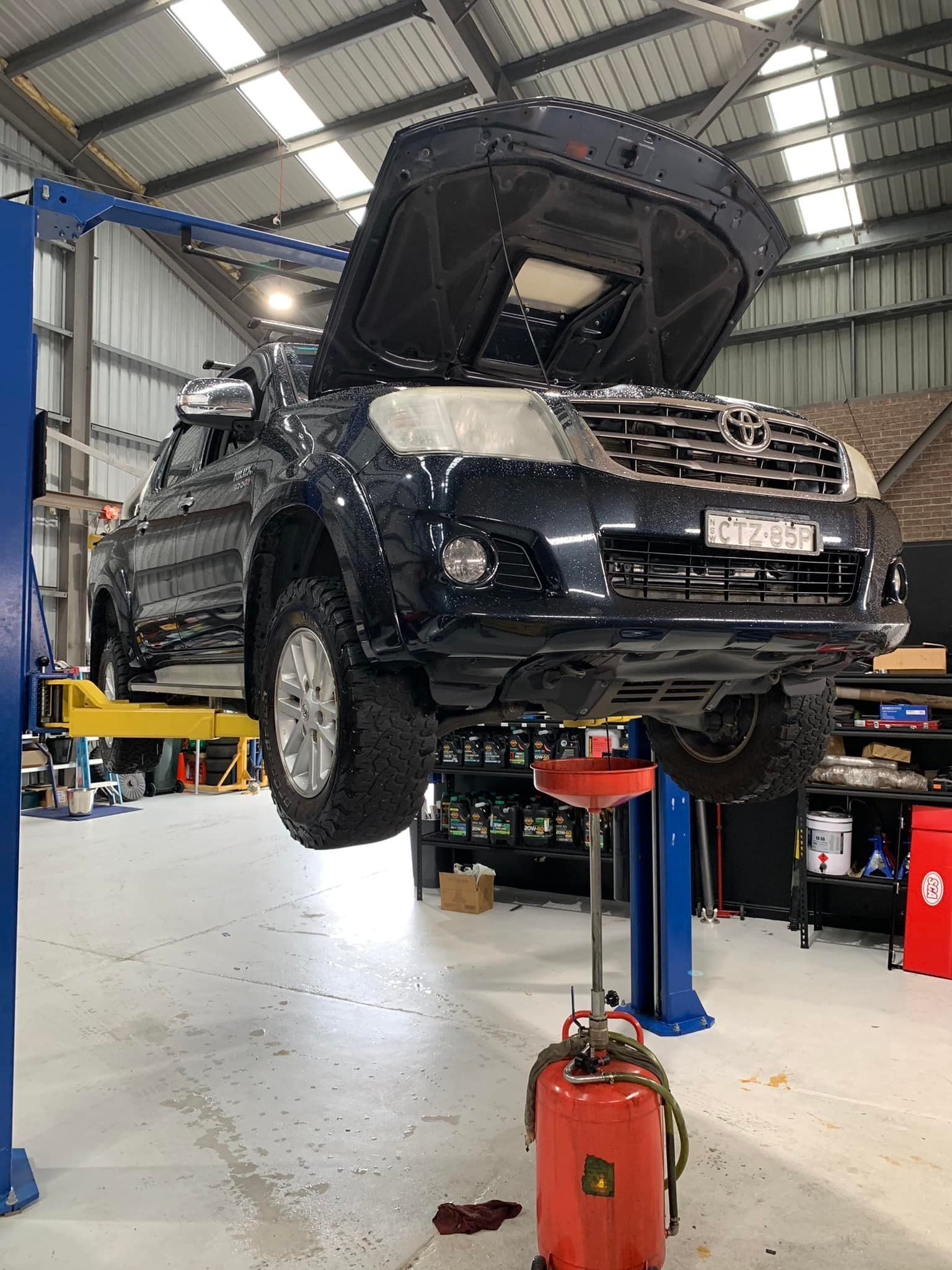 Dark Blue Pickup Truck on a Lift in a Garage — D.A.G Automotive in Unanderra, NSW