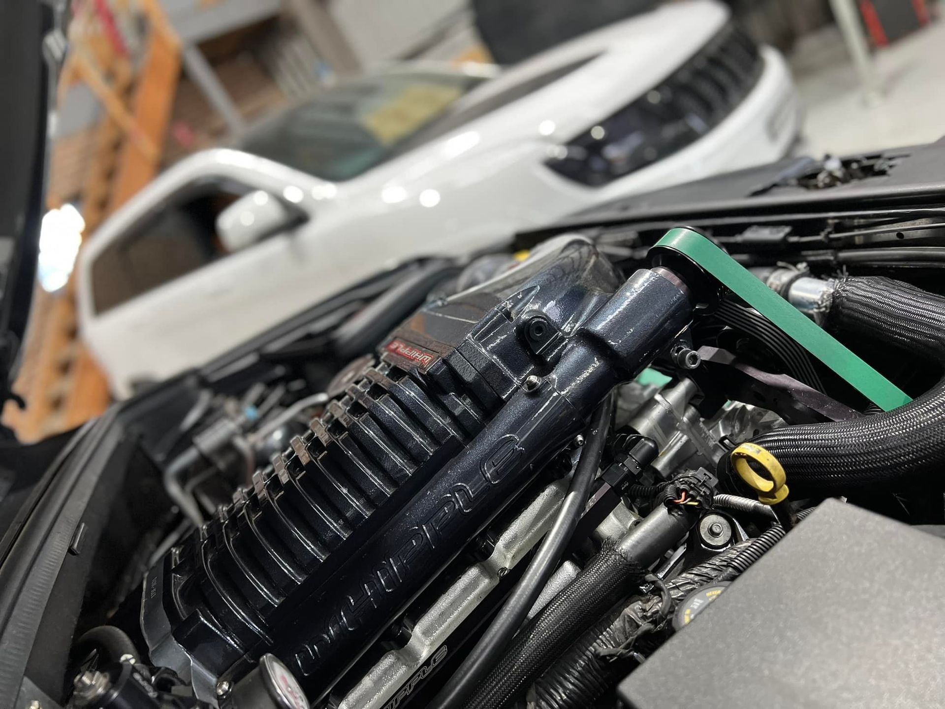 Engine bay of a black vehicle with a supercharger.— D.A.G Automotive in Unanderra, NSW