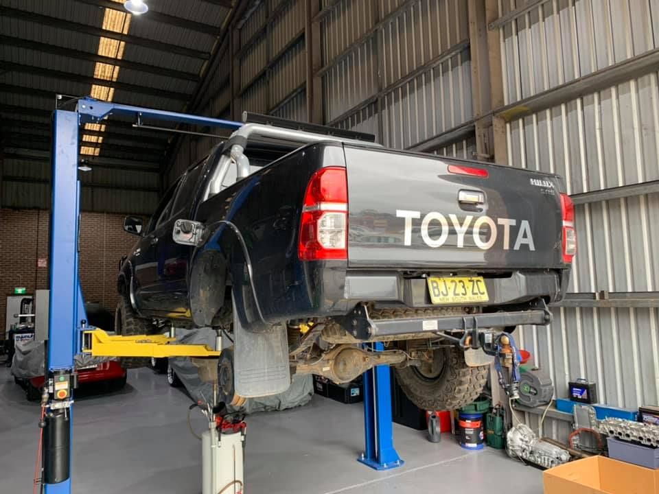 Black Toyota Hilux Truck Elevated on a Hydraulic Lift — D.A.G Automotive in Unanderra, NSW