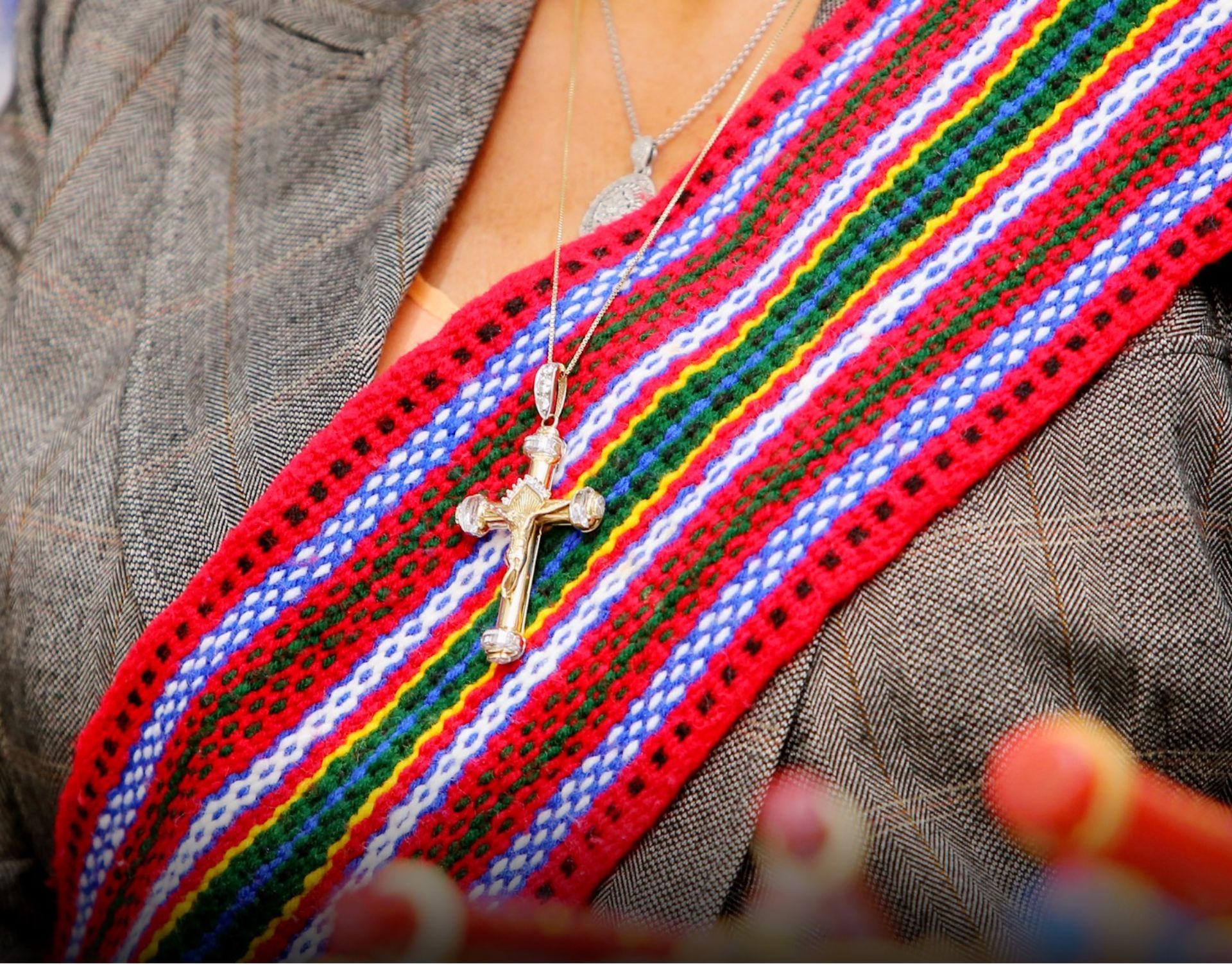 A woman is wearing a necklace with a cross on it