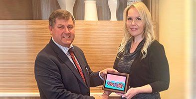 A man in a suit and tie is giving a tablet to a woman.