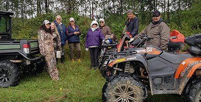 A group of people are standing next to four wheelers in a field.
