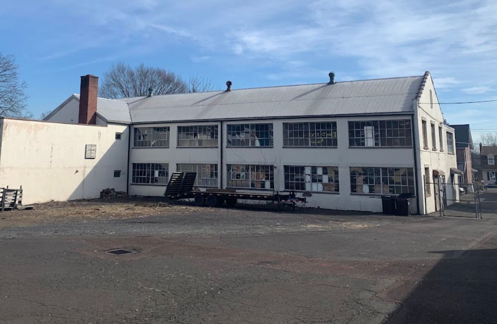 White two-story building with many windows, a flatbed truck in front, and a clear blue sky.
