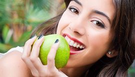 girl with beautiful teeth eating a green apple